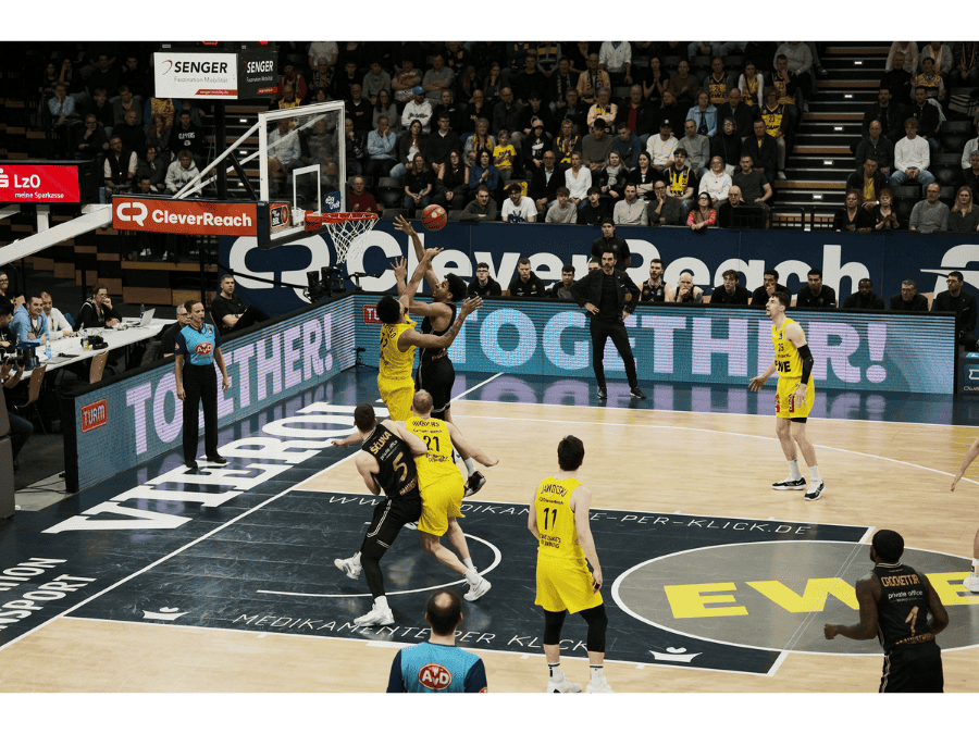 TURM-Sahne x EWE Baskets Basketballspiel, Spieler im Angriff, Werbebande zeigt das Wort Together!